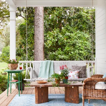 porch with a swing, seating, and plants.