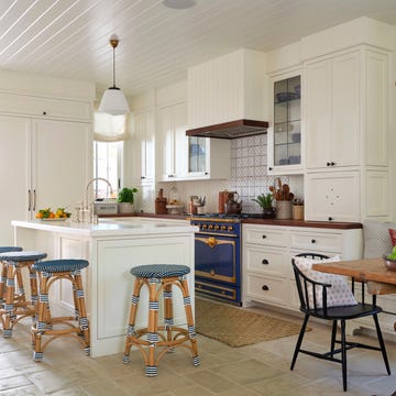 a white kitchen with blue range and blue and white woven bar stools