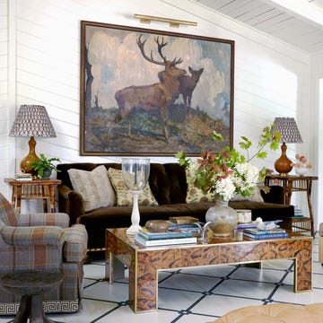 living room with large elk artwork on wall and a brown sofa between two chairs