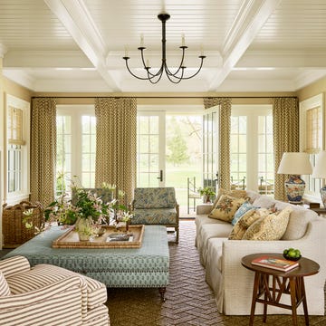 living room with couch and chairs around an ottoman with curtains on the windows